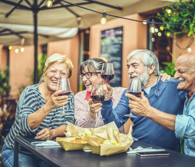 seniors enjoying a glass of wine together outdoors